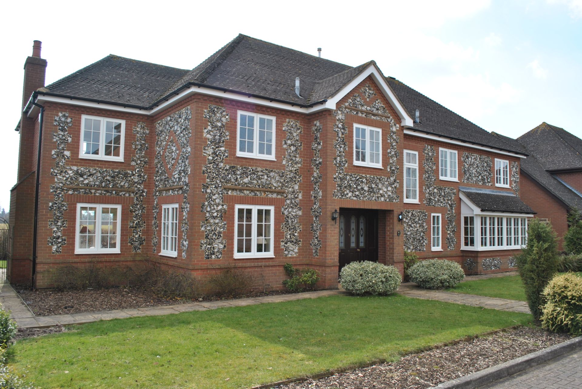White casement windows in a flint-decorated brick Buckinghamshire house
