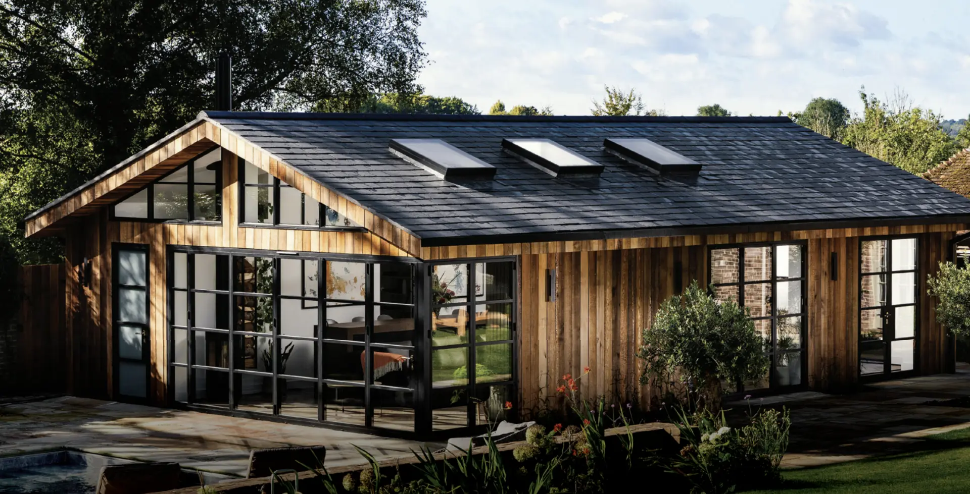 Black Origin aluminium bi-fold doors opening onto a stone patio